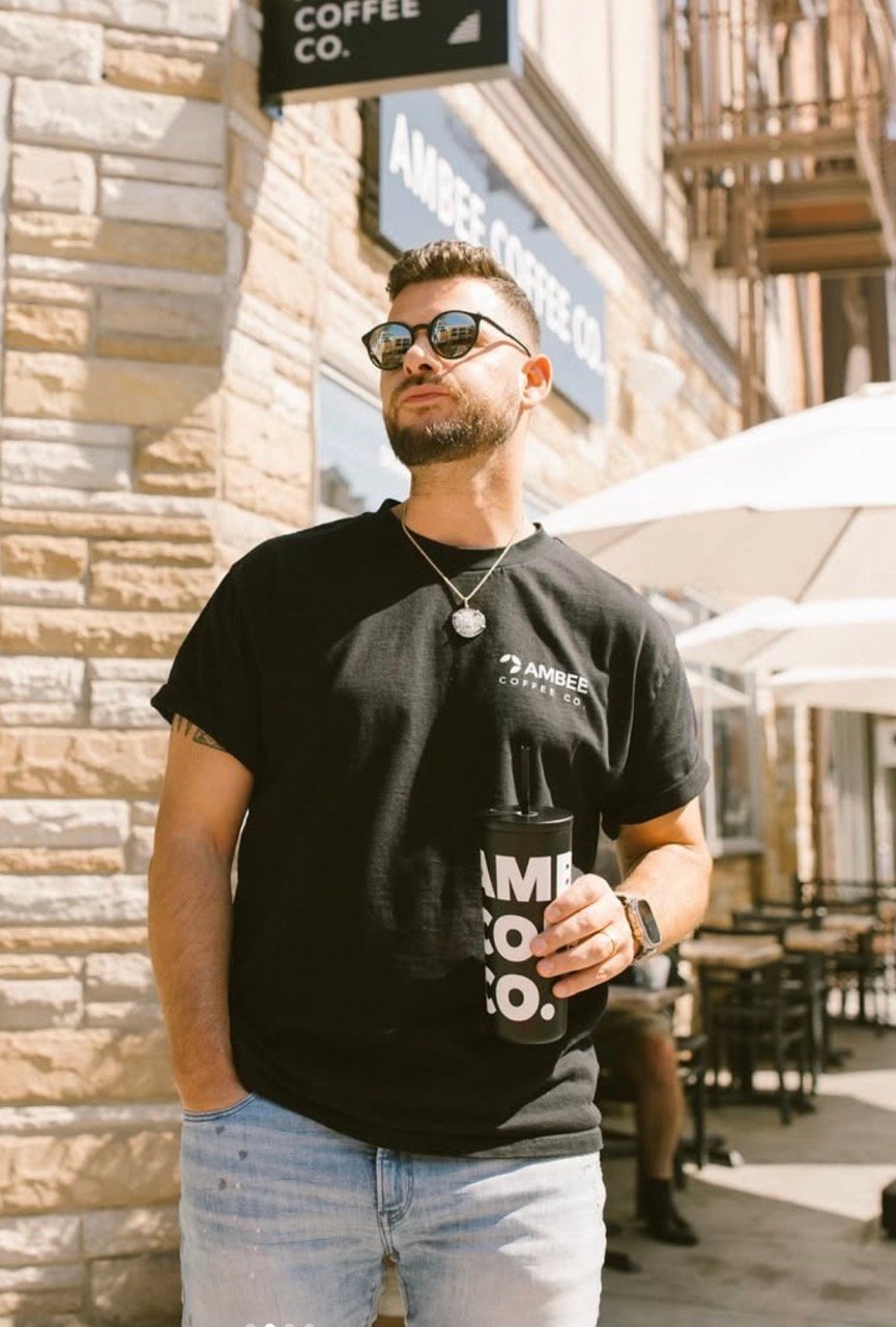 Ambee Coffee Co. founder outside the cafe holding a branded tumbler